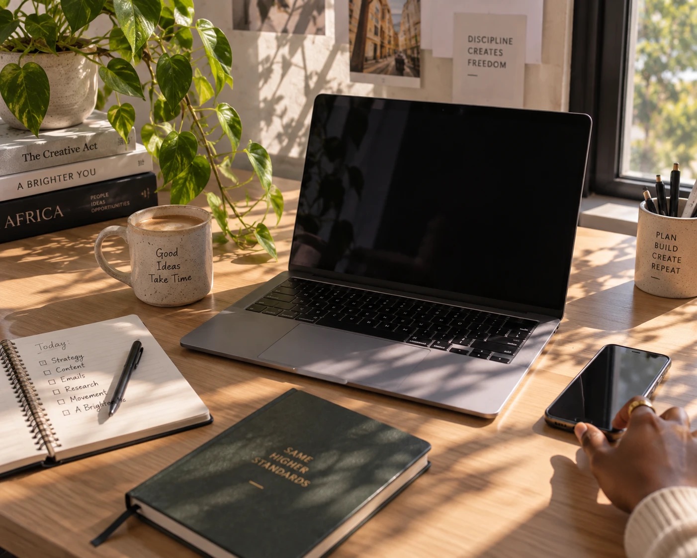 A laptop and a phone side by side on a desk in morning light